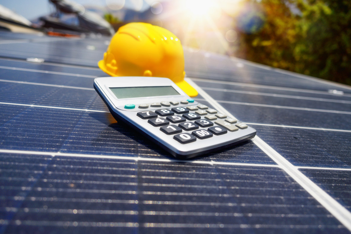 Renewable energy system with solar panels on roof with calculator and hardhat